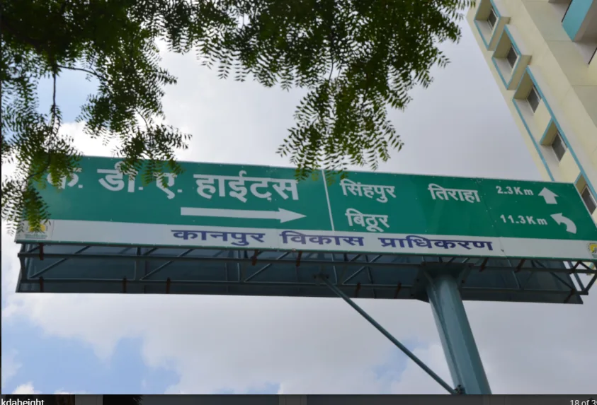 A KDA direction sign to KDA Heights, with Sinhpur crossing 2.3 km and Bithoor 11.3 km. It shows another KDA project, not the plots offered here